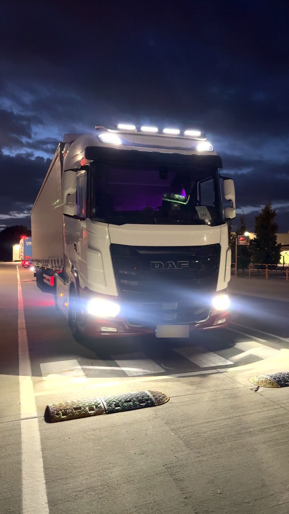 Camion DAF de DAVE LOGISTICS de nuit, phares allumés sur le terminal